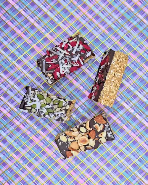  Portioned pieces of the chocolate chickpea slice. Toppings included. Mixed seeds and coconut, goji berries and coconut and mixed nuts. 