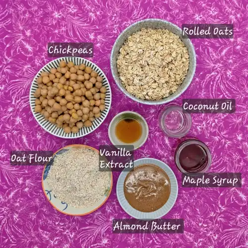  The labelled ingredients used in the Chocolate Chickpea Slice recipe. Chickpeas, rolled oats, oat flour, almond butter, coconut oil, maple syrup, vanilla extract. 