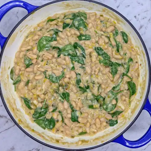 Add a squeeze of lemon juice and the spinach to the cooked Leeky Beans. Lightly wilted spinach leaves.