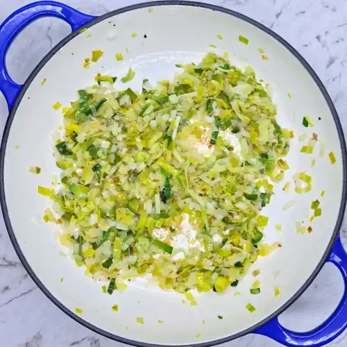 Sliced leeks and finely chopped onion in a frying pan. Lightly caramelised and soft fried leeks and onion.
