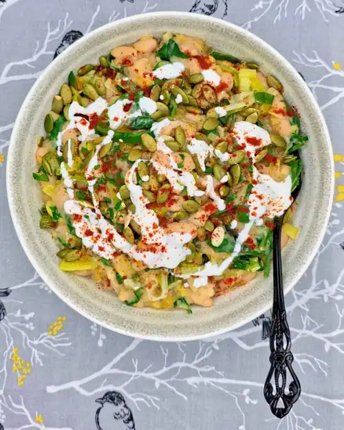Leeky Beans plated in a bowl and topped with a sprinkle of toasted pumpkin seeds, a drizzle of Greek yoghurt and a sprinkle of smoked paprika.