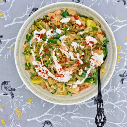 Leeky Beans plated in a bowl and topped with a sprinkle of toasted pumpkin seeds, a drizzle of Greek yoghurt and a sprinkle of smoked paprika.