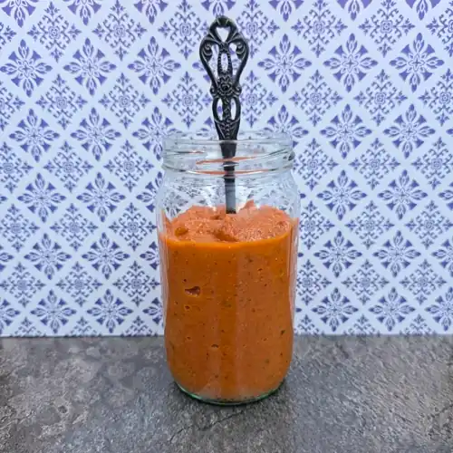 Pureed Ratatouille Pasta Sauce in a glass jar with a fancy tipped serving spoon.