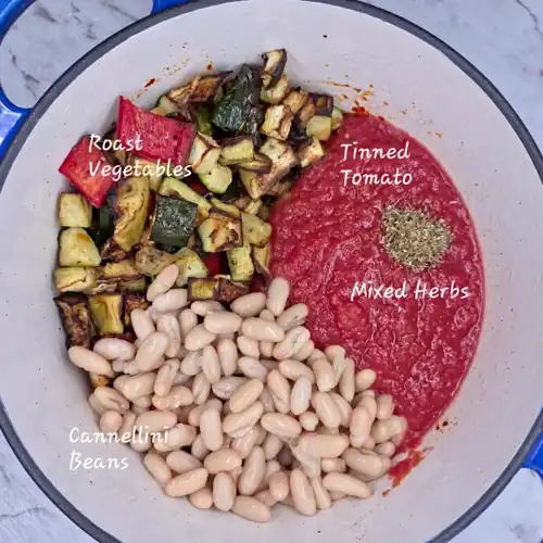 In a pot add the roasted vegetables along with the tinned tomato, cannellini beans and dried mixed herbs. With ingredient labels.