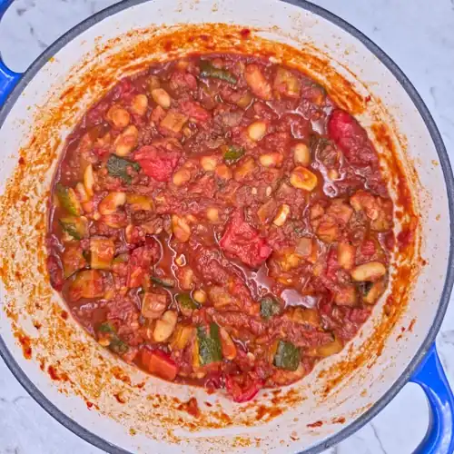 Simmered roasted vegetable tomato sauce and cannellini beans in a pot.