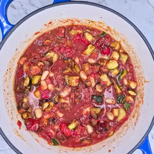 Roasted vegetable tomato sauce and cannellini beans before simmering in a pot.